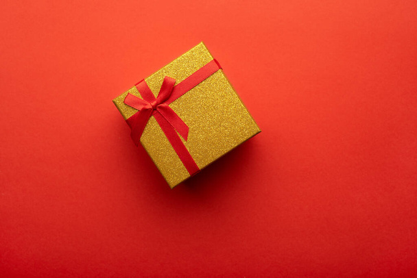 Red and gold gift box on a bright red background. Flat lay, top view. - Фото, зображення
