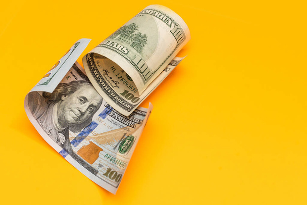 Single Honderd Dollar Bill gekruld op geel - Foto, afbeelding