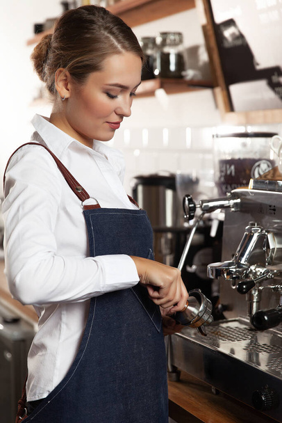 バリスタはコーヒータンプで挽いたコーヒー豆をコーヒーマシンに入れる前に. - 写真・画像