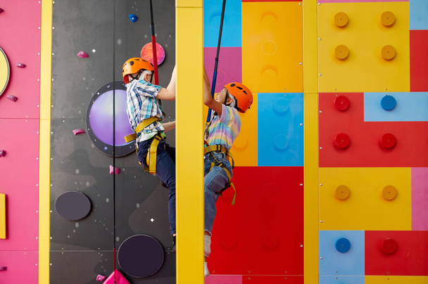 Deux enfants en casque grimpent sur le mur d'escalade - Photo, image