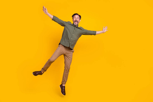 Full length body size view of attractive cheerful funny man jumping having fun isolated over bright yellow color background - Fotoğraf, Görsel