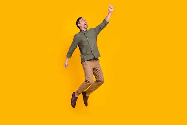 Full length body size view of attractive cheerful man jumping hanging isolated over bright yellow color background - Φωτογραφία, εικόνα