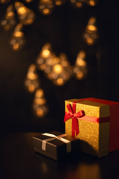Gift boxes in the dark with bokeh lights of a Christmas garland - Zdjęcie, obraz