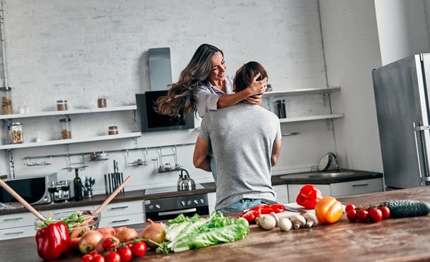Couple romantique dansant dans la cuisine. Beau homme et jolie jeune femme s'amusent ensemble tout en faisant de la salade. Concept de mode de vie sain. - Photo, image