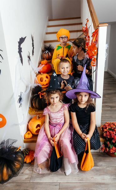 Halloween holiday party for children. Kids in costumes on staircase - Foto, afbeelding