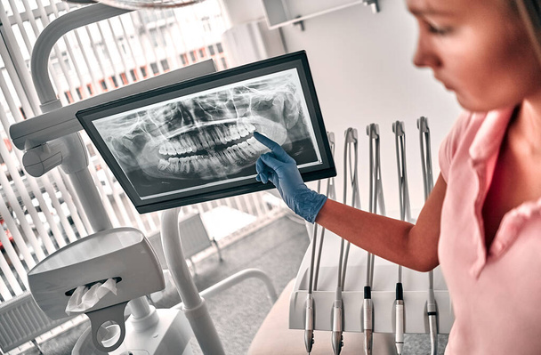 Obrázek lékaře nebo zubního lékaře prezentující zubní rentgenový film doporučuje pacienta v léčbě zubní a zubní lékařství, pracuje na pracovišti. - Fotografie, Obrázek