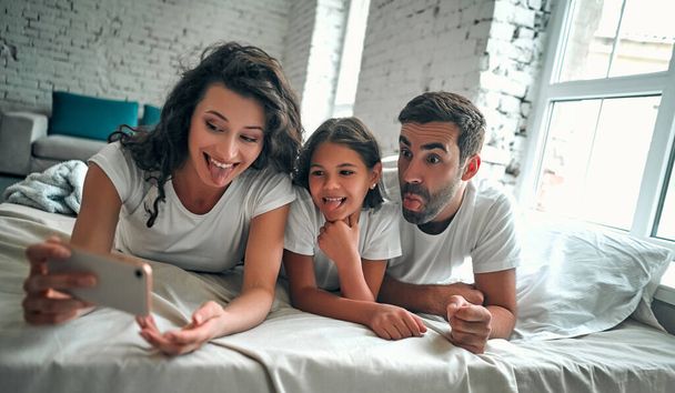 Boldog fiatal család készítsen önarcképet okos telefonnal. - Fotó, kép