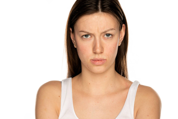Vihainen nuori nainen ilman meikkiä, valkoisella taustalla - Valokuva, kuva