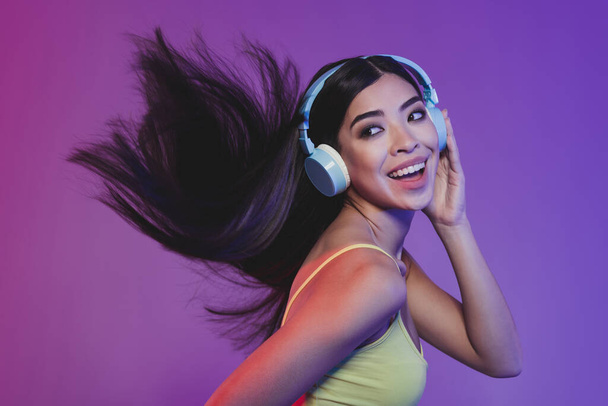 Profile photo of funky trendy millennial brunette lady listen music look empty space wear yellow top headphones isolated on neon pink color background - Фото, изображение
