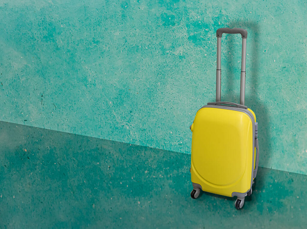 A wheeled suitcase displayed on a green wall - Fotó, kép