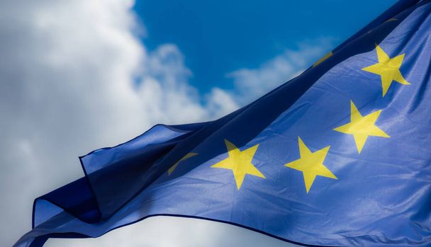 Επίσημη σημαία της Ευρωπαϊκής Ένωσης μπροστά από γαλάζιο ουρανό. - Φωτογραφία, εικόνα