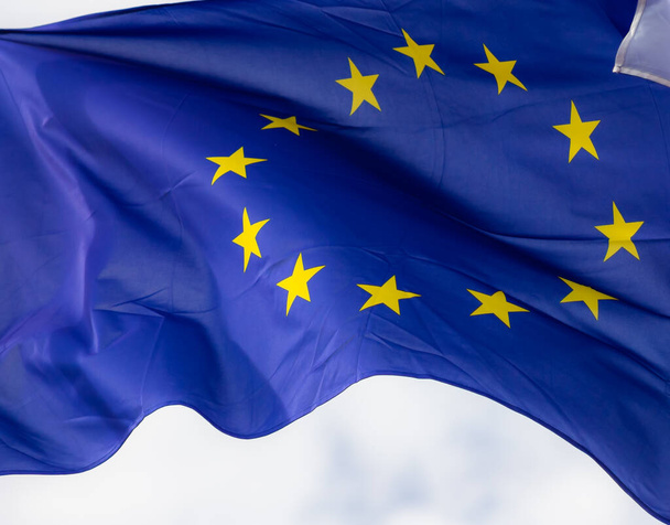 Επίσημη σημαία της Ευρωπαϊκής Ένωσης μπροστά από γαλάζιο ουρανό. - Φωτογραφία, εικόνα