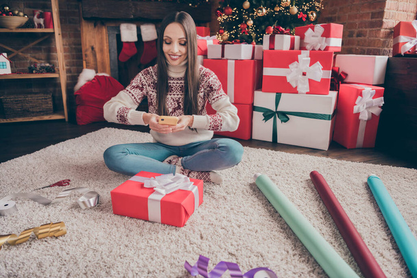 Portrait of attractive cheerful woman sitting on carpet taking photos of giftboxes workshop service at decorated loft home indoors - Photo, image