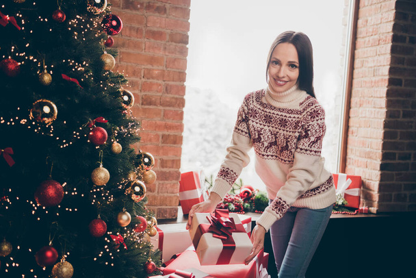Portrait of attractive careful cheerful woman preparing giftboxes festal time day christmastime at decorated loft home indoors - Foto, afbeelding