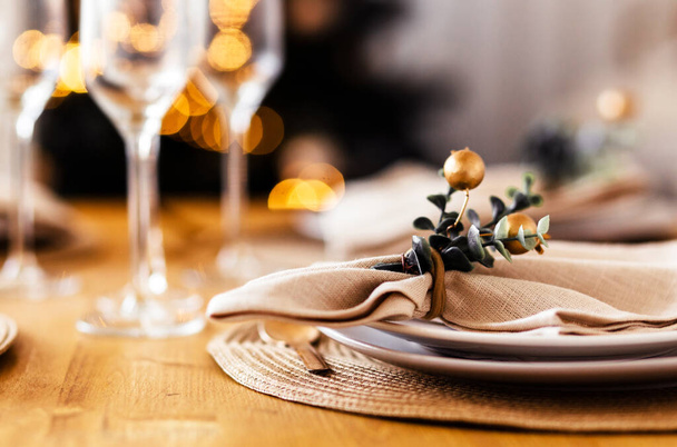Nastavení novoroční tabulky. Talíř s ubrousky a dekorem, sklenice na šampaňské v pozadí. Fotografie - Fotografie, Obrázek
