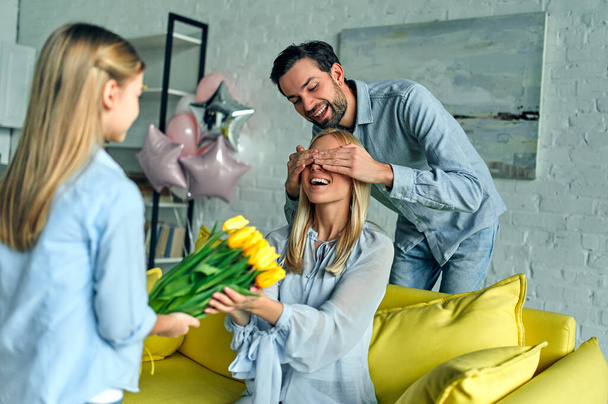 Szczęśliwego Dnia Matki! Ojciec i córka gratulują matce i dają jej kwiaty tulipany. - Zdjęcie, obraz