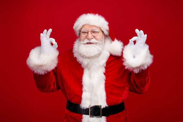 Photo of confident handsome man pensioner dressed santa claus costume showing okey signs smiling isolated red color background - Fotoğraf, Görsel