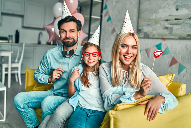 Születésnapi buli. A család megünnepli a lánya születésnapját, jól érzik magukat a partin, szülinapi kalapot viselnek. Családi pillanatok.. - Fotó, kép