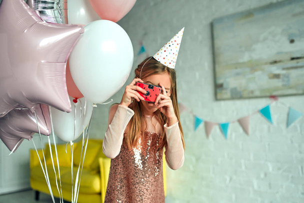 ¡Feliz cumpleaños! Fiesta de cumpleaños. Una chica guapa toma una foto. La habitación está decorada con globos. - Foto, Imagen