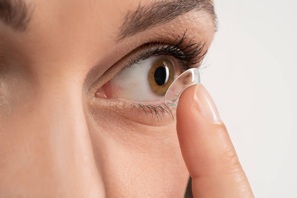 zbliżenie soczewki oka na palcu żeńskim w pobliżu oka - Zdjęcie, obraz