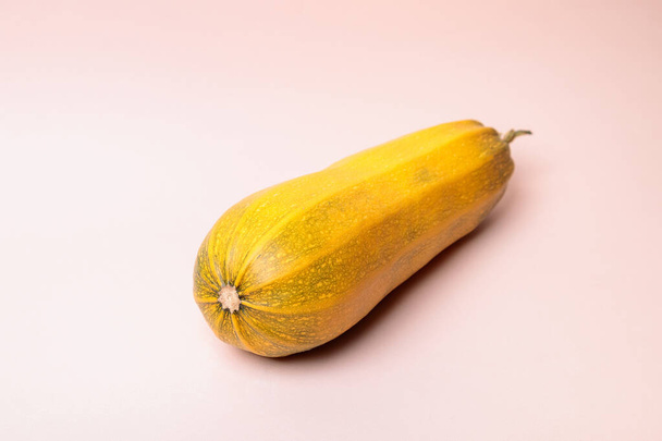 Yellow ripe zucchini on a pink background. - Foto, afbeelding