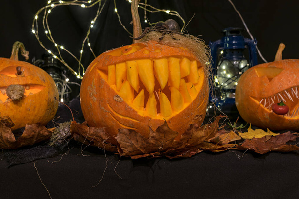 Halloween thema, gesneden pompoen met een enge glimlach, brandende kaarsen, spinnen en spinnenwebben, afschuwelijke schedels, decoratie en vakantie concept, gesneden pompoen voor een leuk feestje, Jack O 's lantaarn - Foto, afbeelding