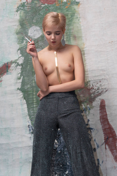 young beautiful woman posing nude in studio, smoking - Фото, изображение