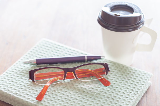 Poznámkový blok, tužku brýle a šálek kávy na dřevěný stůl - Fotografie, Obrázek