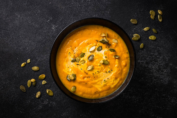 Pumpkin soup puree with cream and spices in black bowl. - Photo, Image
