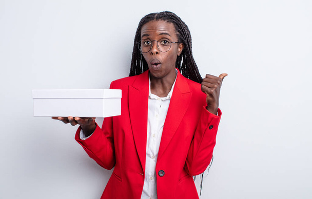 pretty black woman looking astonished in disbelief. businesswoman with a white box - Фото, зображення