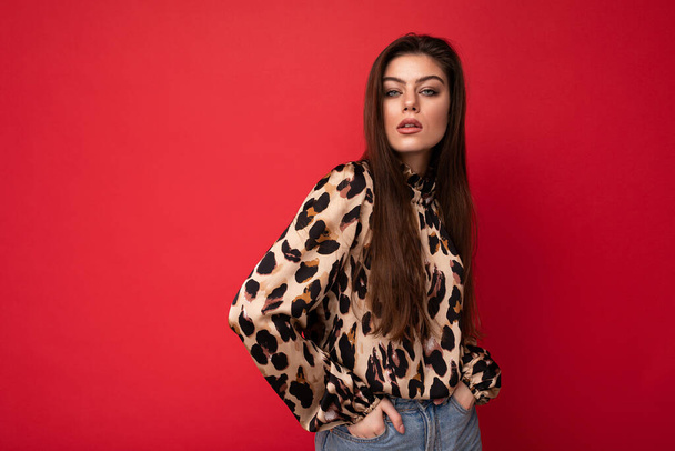 Close-up portrait of young nice-looking attractive lovely glamorous brunet woman wearing leopard blouse isolated on red color background with free space - Foto, Imagen