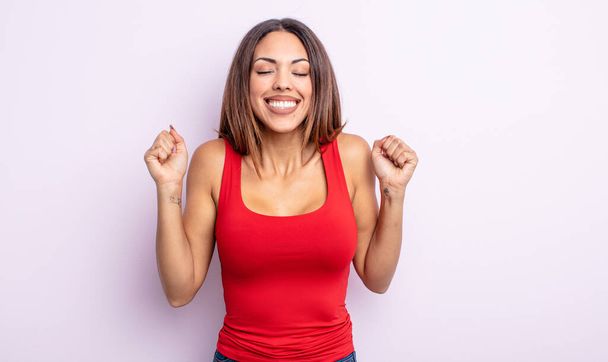 pretty hispanic woman looking extremely happy and surprised, celebrating success, shouting and jumping - Foto, imagen