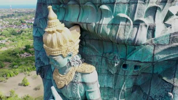 Garuda Wisnu Kencana GWK Bali monument zavřít naklonit dolů za slunečného dne s modrou oblohou a mraky. Letecký záznam z bezpilotního letounu - Záběry, video