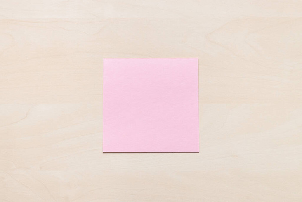 top view of blank pink sheet of note paper on light brown wooden board - Fotografie, Obrázek