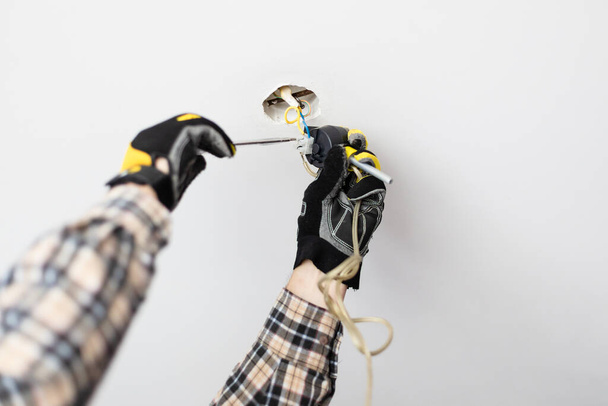 electrician repairing electrical wiring of ceiling lamp at home - Foto, Imagen
