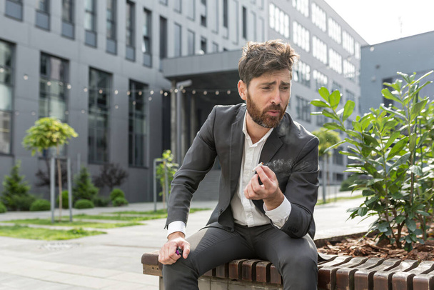Male businessman smoking cigarette in the air near the office relieves stress after a hard day's work, tired reworked depressed - Фото, изображение
