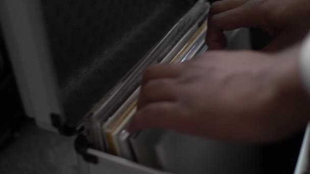 Zbliżenie zdjęcia DJ-a przeszukującego jego kolekcję muzyki, próbującego znaleźć album, który ma na myśli do następnego utworu. - Materiał filmowy, wideo