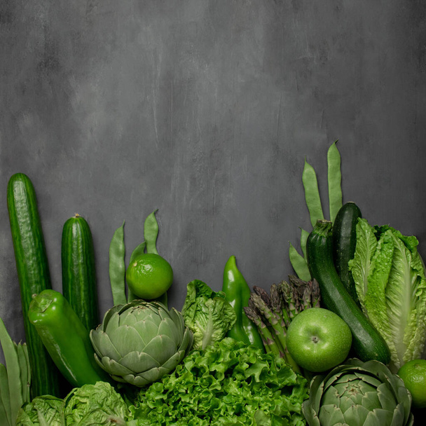 Ассортимент зеленых овощей и трав на сером каменном фоне. Копирование пространства - Фото, изображение