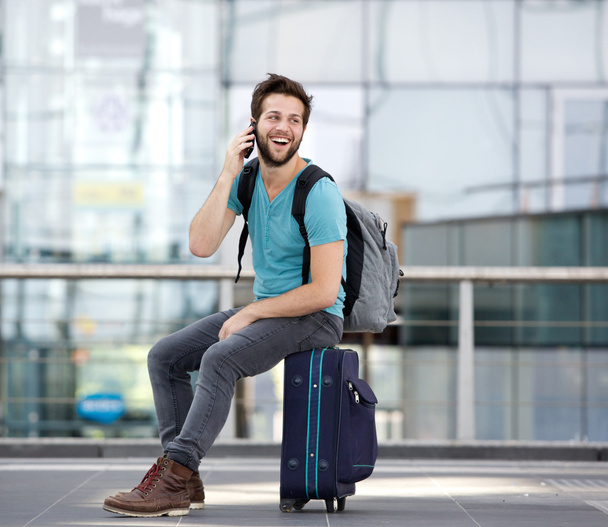 jonge man die door mobiele telefoon op de luchthaven - Foto, afbeelding