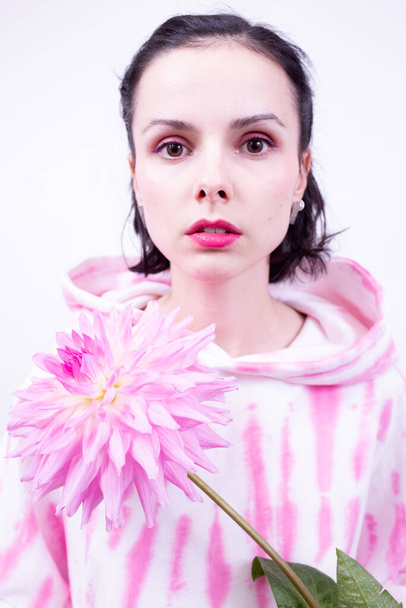 woman in a pink hoodie holding a pink flower - Photo, image