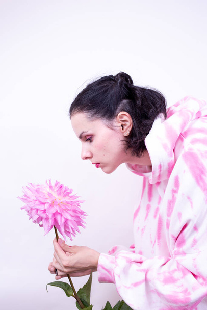 woman in a pink hoodie holding a pink flower - Фото, зображення