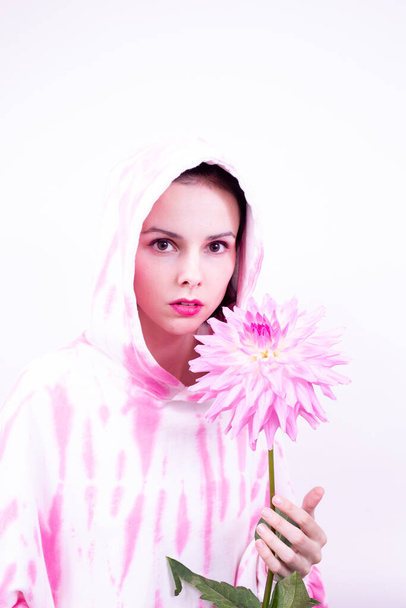 woman in a pink hoodie holding a pink flower - Φωτογραφία, εικόνα