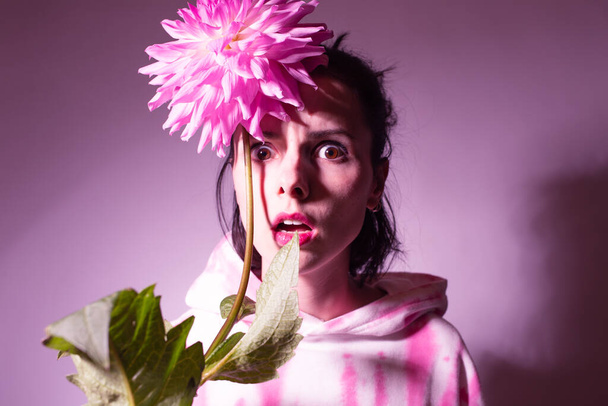 woman in a pink hoodie holding a pink flower - Zdjęcie, obraz