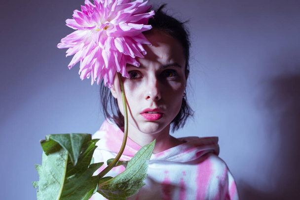 woman in a pink hoodie holding a pink flower - Photo, Image