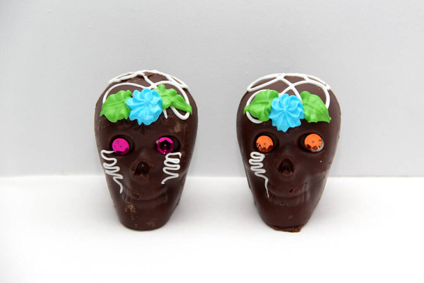 Schokoladenbonbons in Form eines traditionellen Totenkopfes vom Altar mit Totenbrot, Cempasuhil und Kerze zum Tag der Toten und Allerheiligen, der in Mexiko gefeiert wird - Foto, Bild