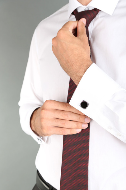 Man doing collar button up on grey background - Zdjęcie, obraz