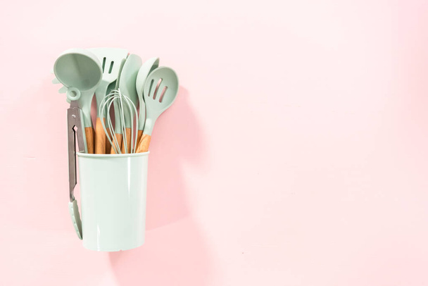Flat lay. New blue silicone kitchen utensils with wooden handles on a pink background. - Photo, Image
