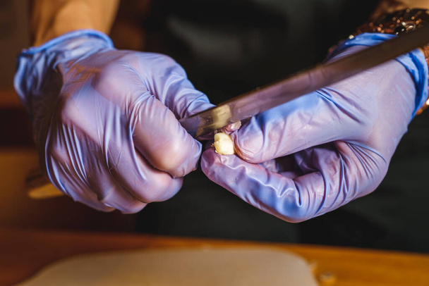 Close up on hands of unknown man or woman cutting peeling garlic cutting using knife - Zdjęcie, obraz