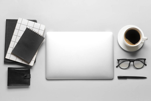 Portátil, billetera, taza de café y herramientas de oficina sobre fondo gris - Foto, imagen
