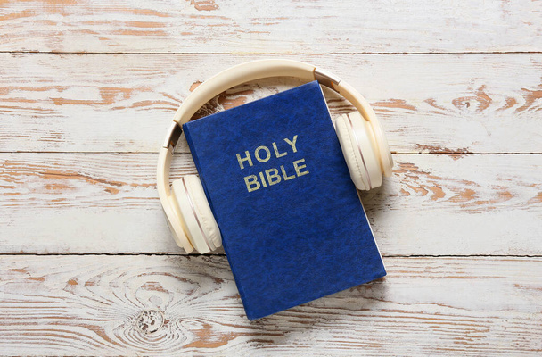 Bíblia Sagrada e fones de ouvido modernos em fundo de madeira clara - Foto, Imagem